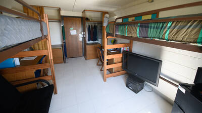 Double room in Horan Hall (viewed from the wall opposite the door) with two beds, chairs, desks, and closet spaces.