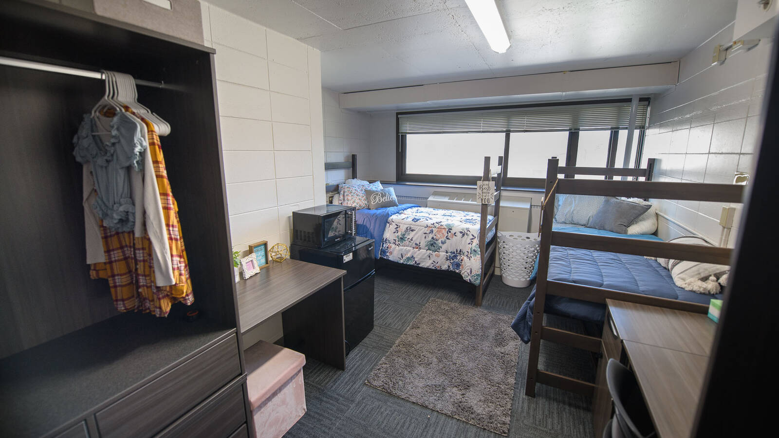 Double room in Towers Hall with two beds, desks, chairs, a mini fridge, closet spaces, and a big window.