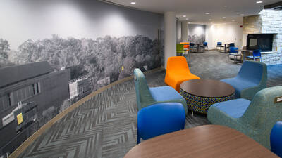 Common space in Towers Hall with colorful chairs, tables, and a big mural.