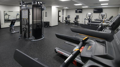 Fitness room in Towers Hall with cardio and strength equipment and large mirrors.