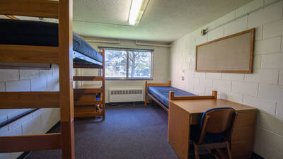 Murry Hall room with two beds, one lofted, two desks, chairs, and a big window.