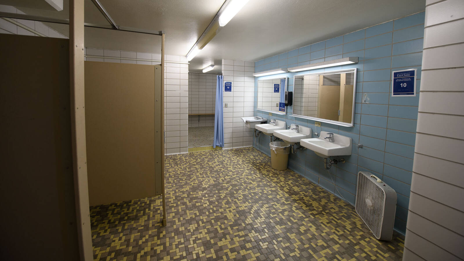Murry Hall bathroom with sinks, stalls, showers, tiled floors.