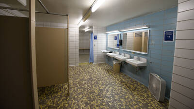 Murry Hall bathroom with sinks, stalls, showers, tiled floors.