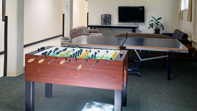 Common space in Murry Hall with foosball table, ping pong table, couches, and a TV.
