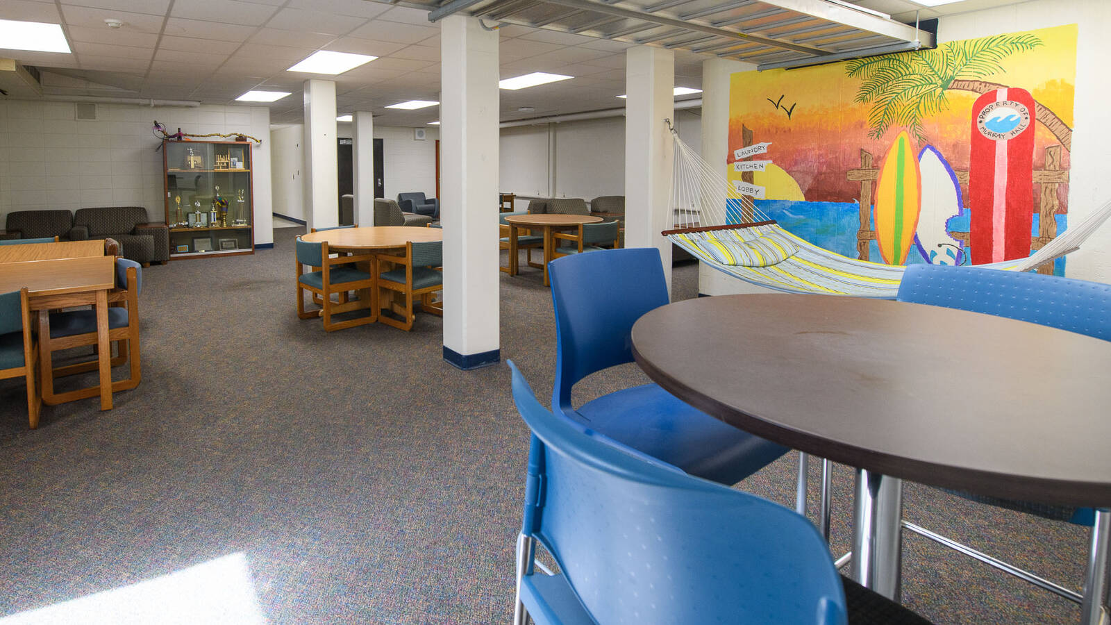 Lounge space in Murry Hall with tables and chairs and a mural on the wall.