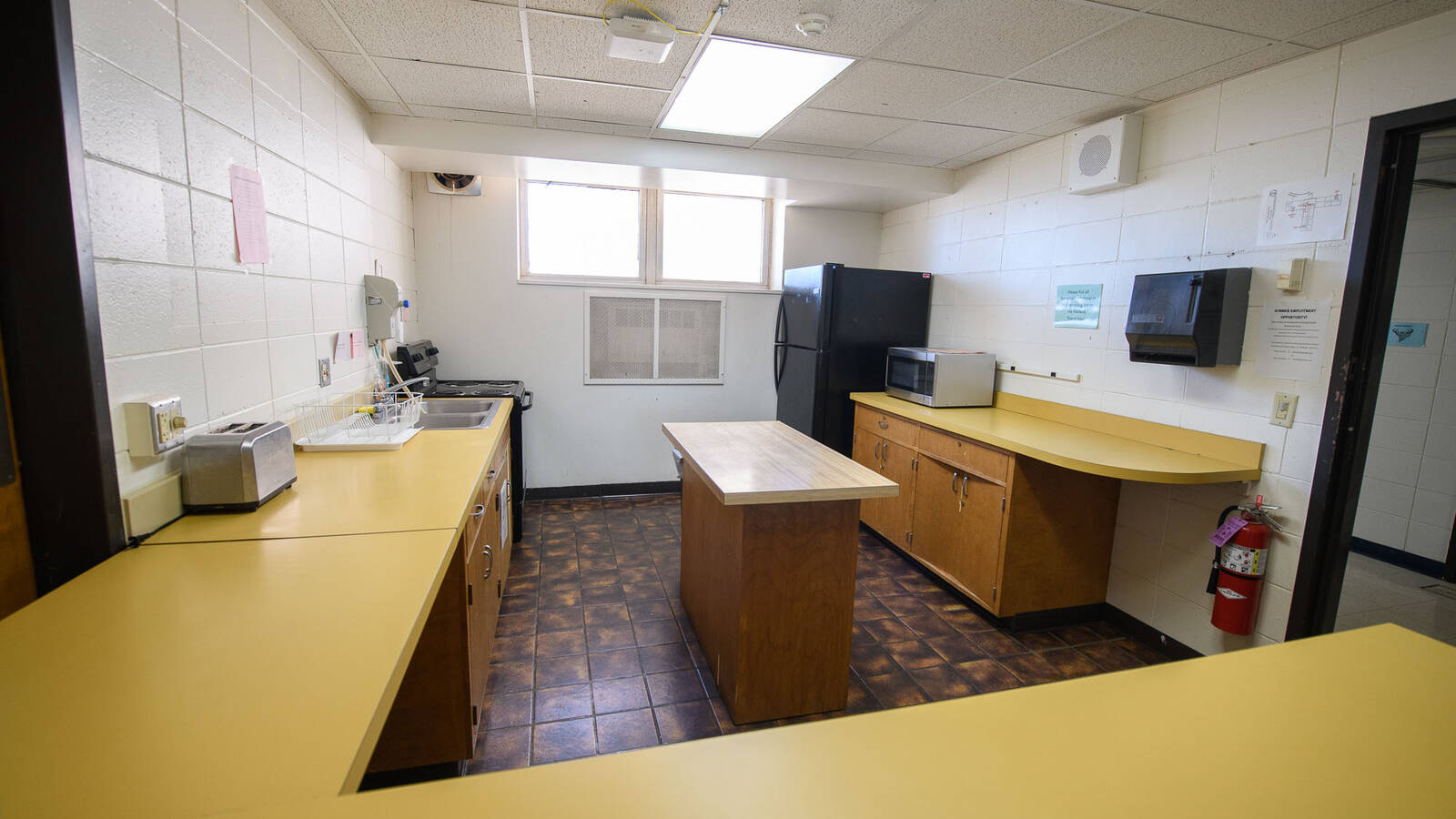 Kitchen area in Murry Hall with an oven/stove, fridge, microwave, toaster, cabinets, and counter space.