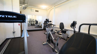 Fitness room in Murry Hall with cardio equipment and big mirrors.