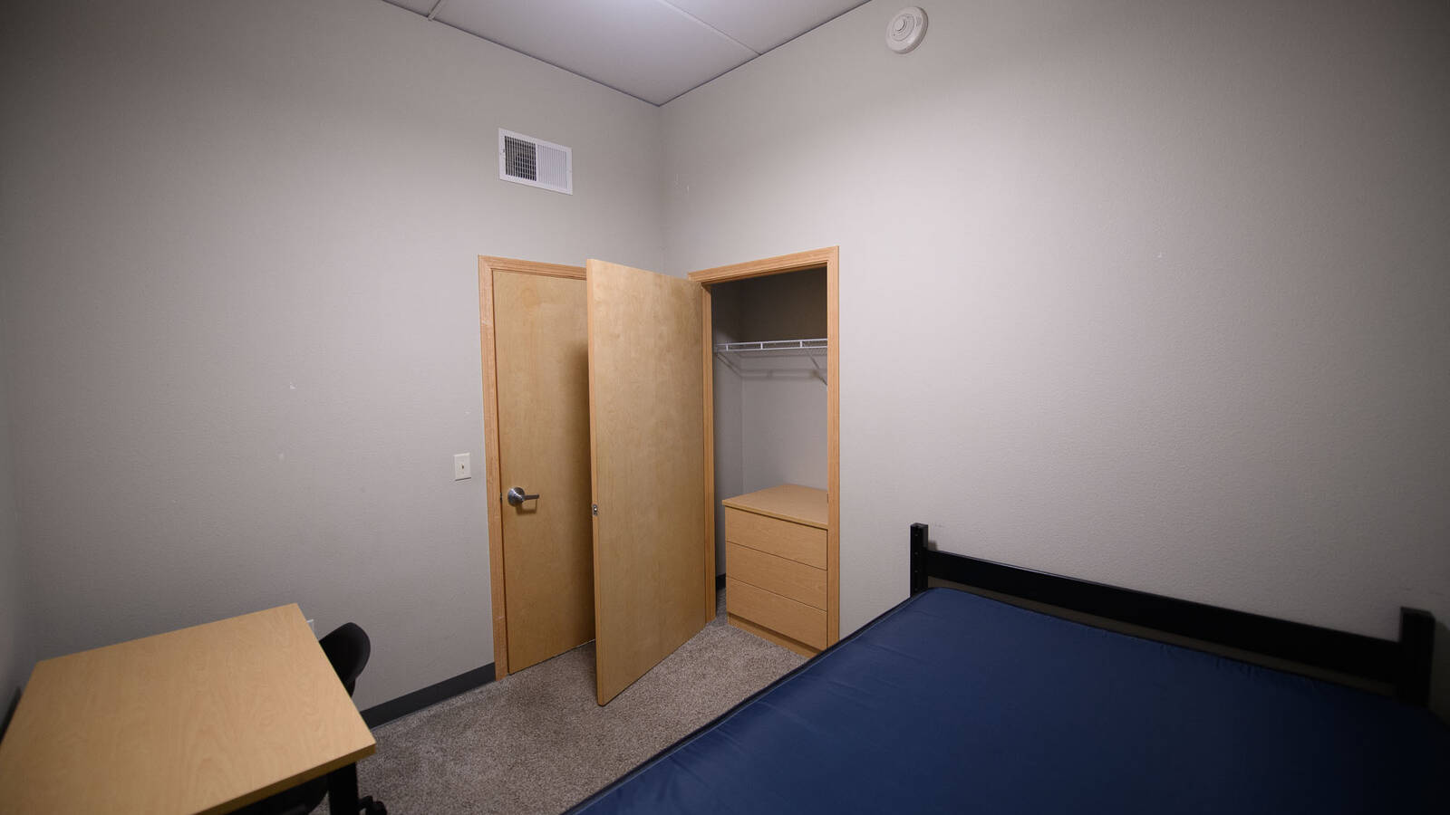 Residence hall bedroom with view of the closet and desk