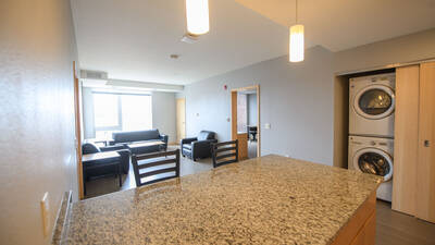 View from residence hall unit kitchen, showing living area and laundry access.