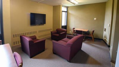 Common space in Priory Hall with TV, couches and a table and chairs.