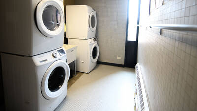 Laundry room in Priory Hall with stacked front-loading washers and dryers.