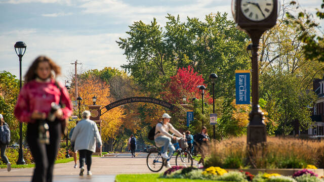 Students walk and bike on Garfield Ave in front of the UW Eau Claire arch.