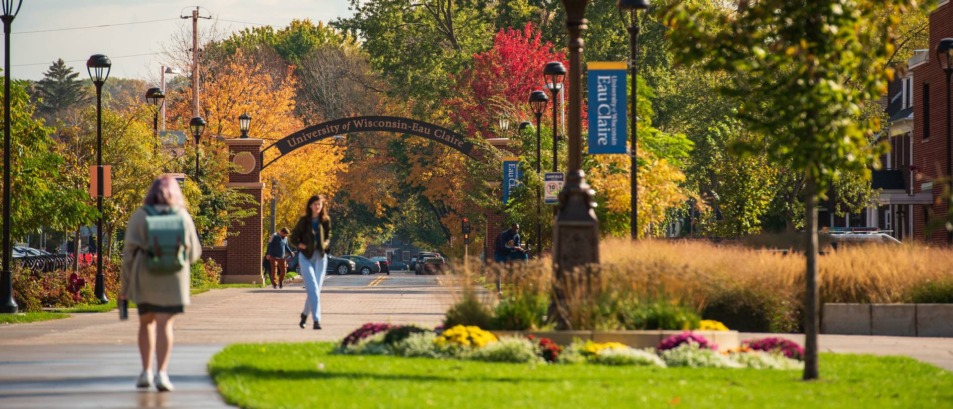 Students walk on Garfield Ave with UW Eau Claire arch in background.