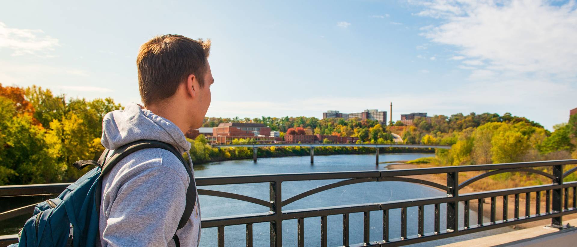 Student crosses foot bridge on a fall day.