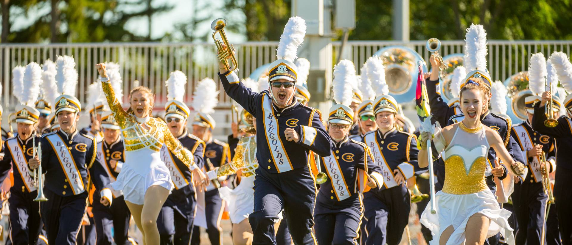 Marching band in full uniform runs onto a football field