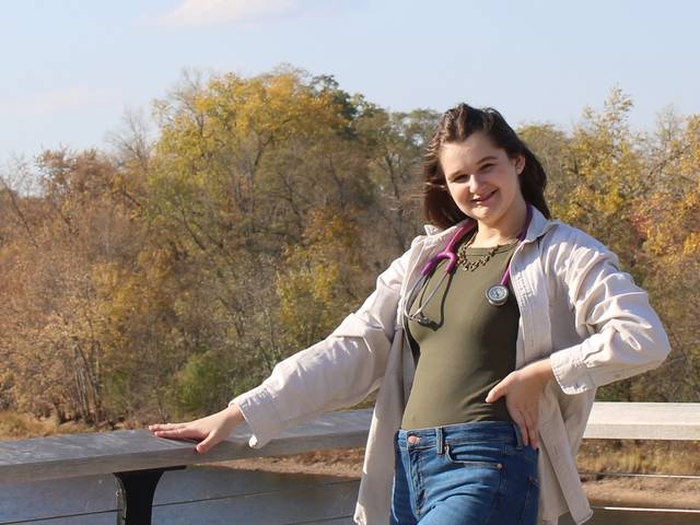female student posing for portrait along the Chippewa River waterfront on campus