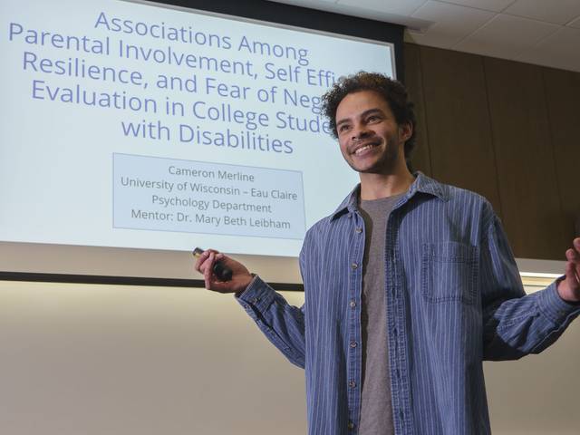 student presenting research in large classroom with white board