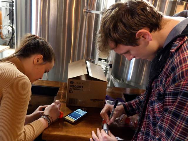 two students in local brewery labeling beer samples for testing