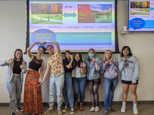 Students standing in front of a projector screen smiling