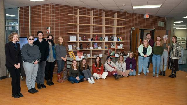 students stand in front of their art projects