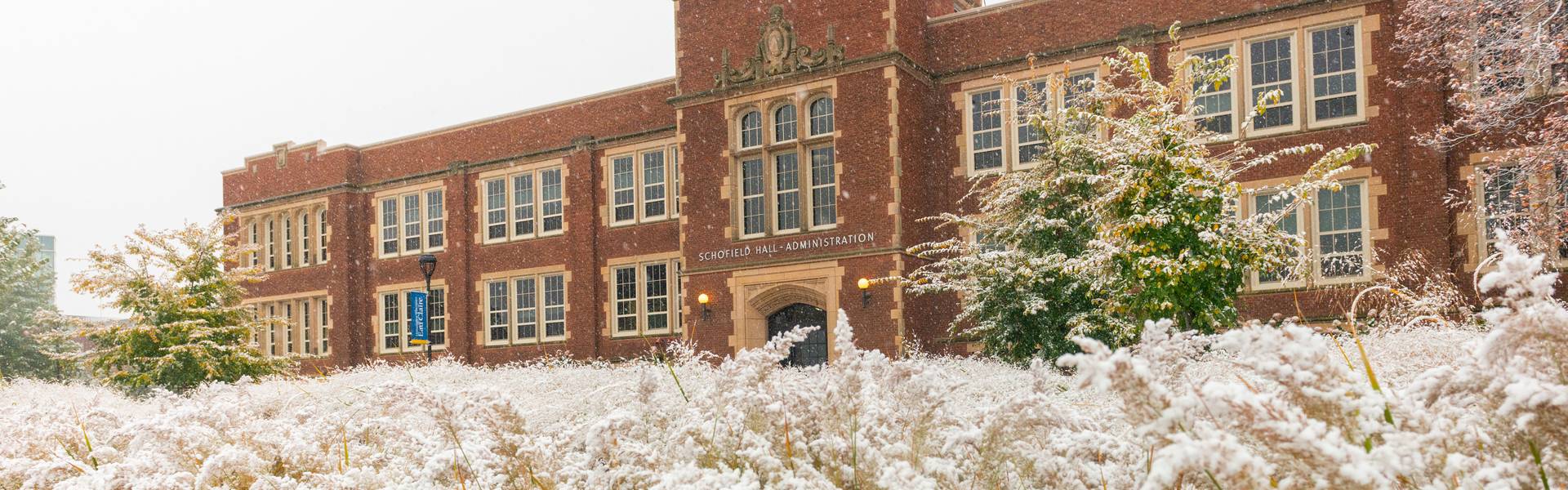 Schofield Hall in the background of snowy wild grasses.