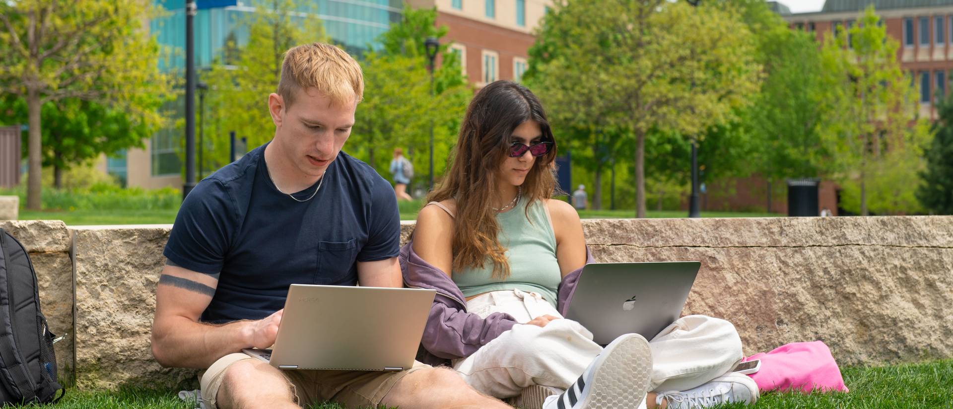 Two students studying on the Campus Mall during the Spring.