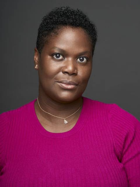 Toya Wolfe, a black woman with close cropped hair looking at the camera with interest