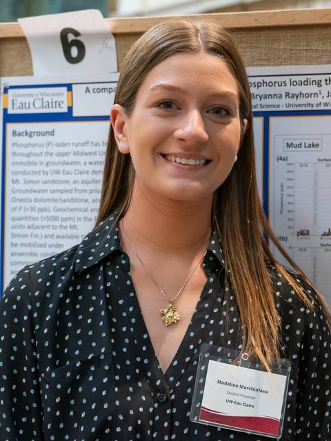 Female student smiling, research poster behind her