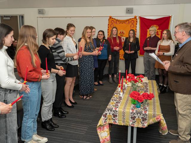 A group standing holding candles while a man reads