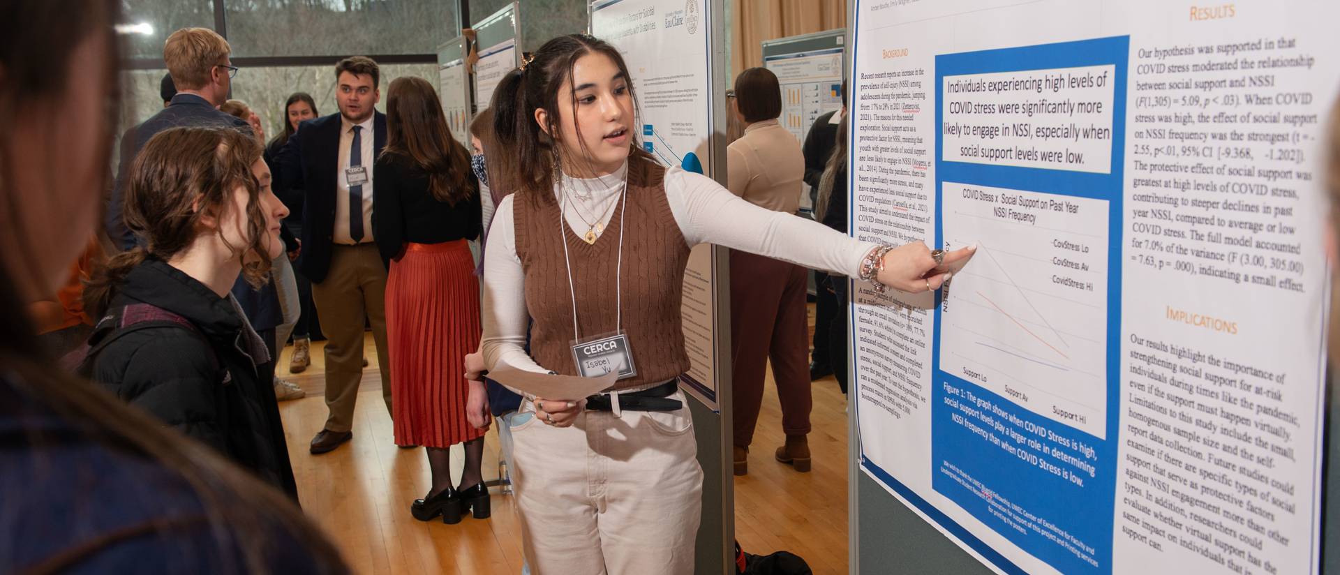 Student points to a research poster while presenting during a session