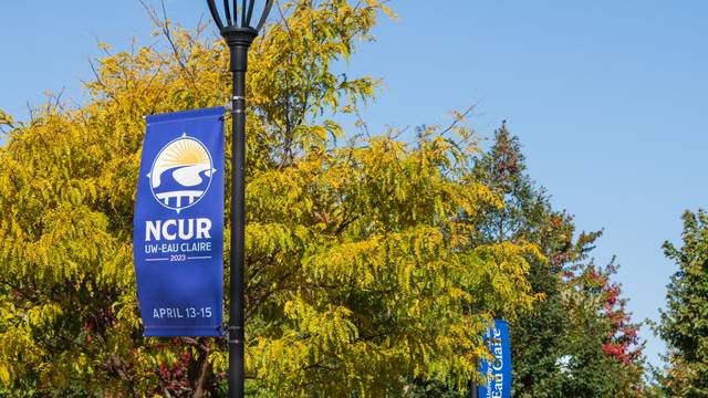 Lightpole banner on campus that reads "NCUR UW-Eau Claire 2023 April 13-15"