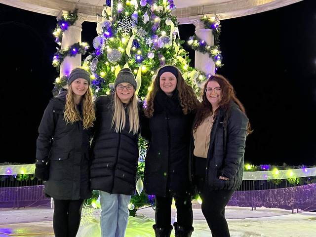 four girls in front of an outdoor Christmas tree