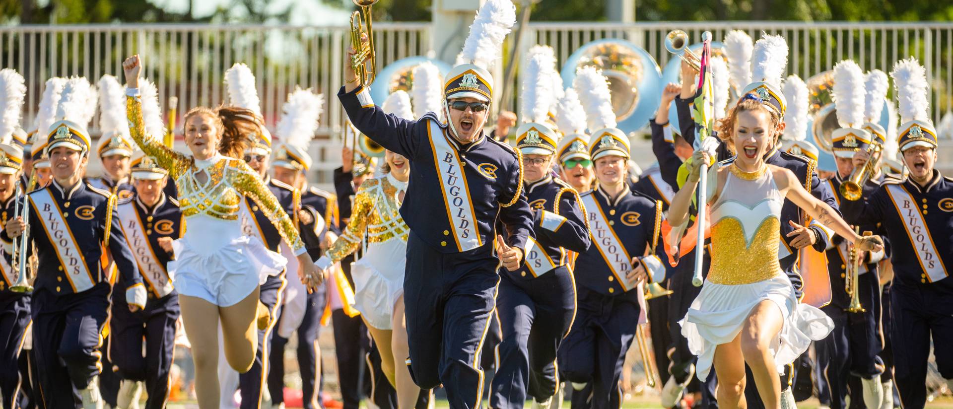 Members of the Blugold Marching Band race down the field during a halftime performance at a football game.