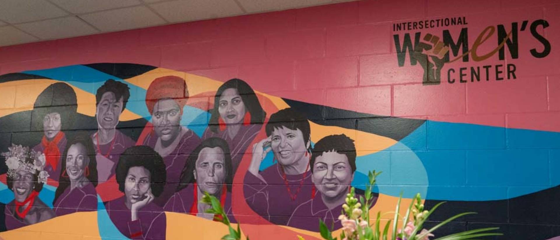 A wall painted with influential women's portraits and the title of Intersectional Women's Center