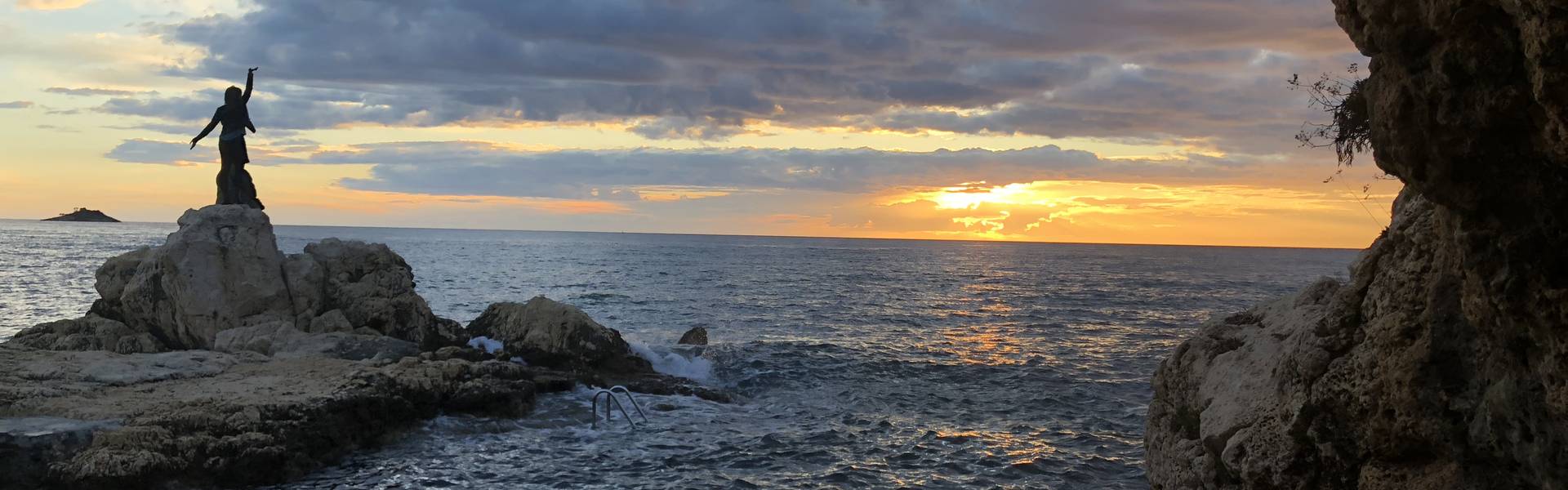 Girl standing on a rock in the ocean and sunset