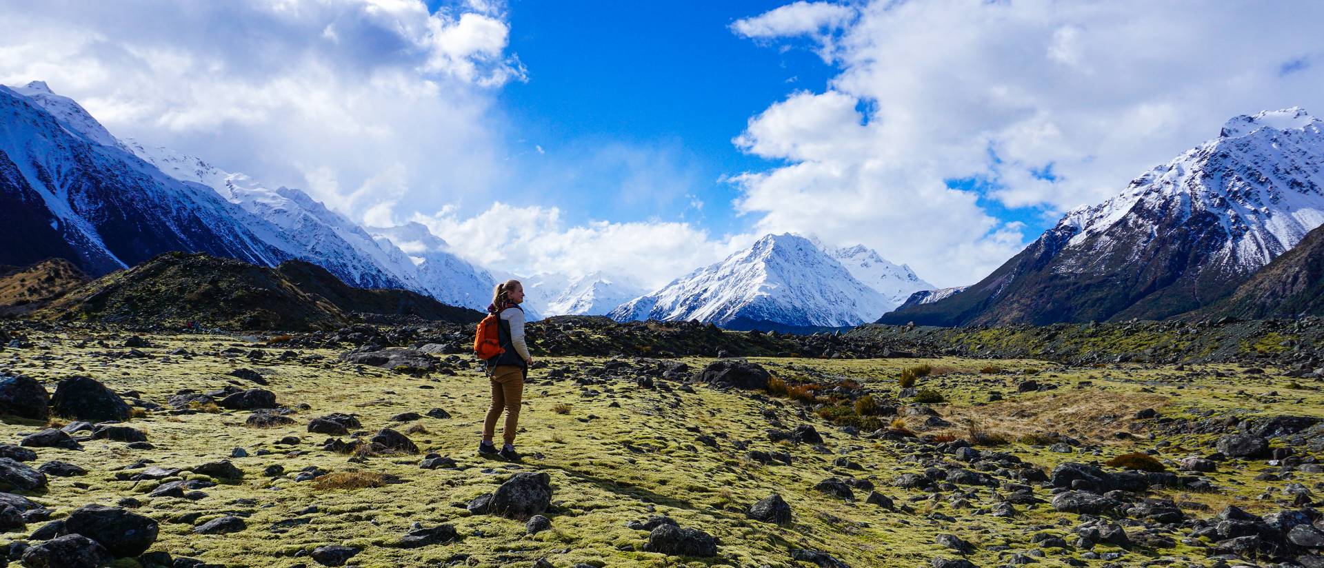 Student standing in a mountain vista, sunny day snow capped mountains