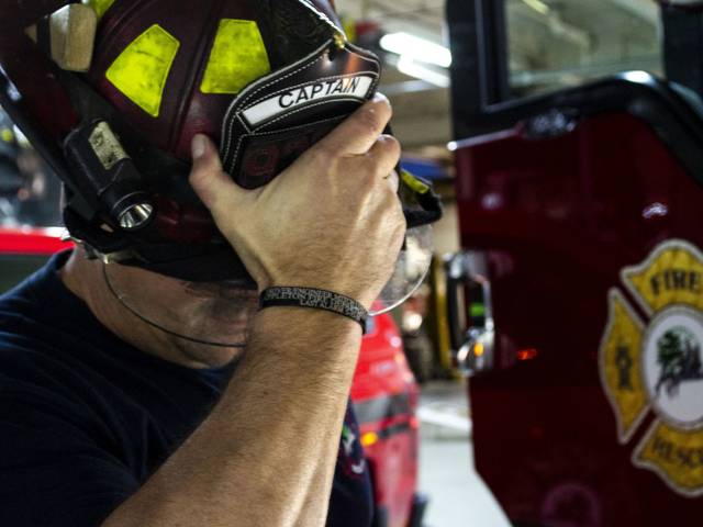 photograph of firefighter with hand over helmet