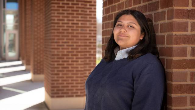 female student outside Centennial Hall leaning on brick column