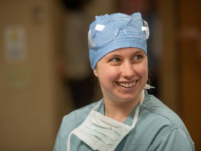 female student in full scrubs, mask down, smiling