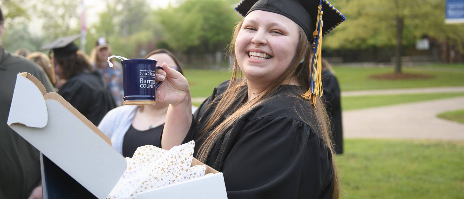 female graduate holding a UW-Eau Claire Barron County coffee mug