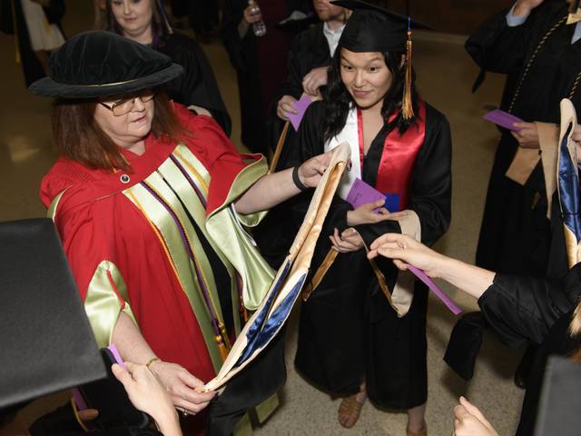 graduates and faculty backstage preparing for commencement