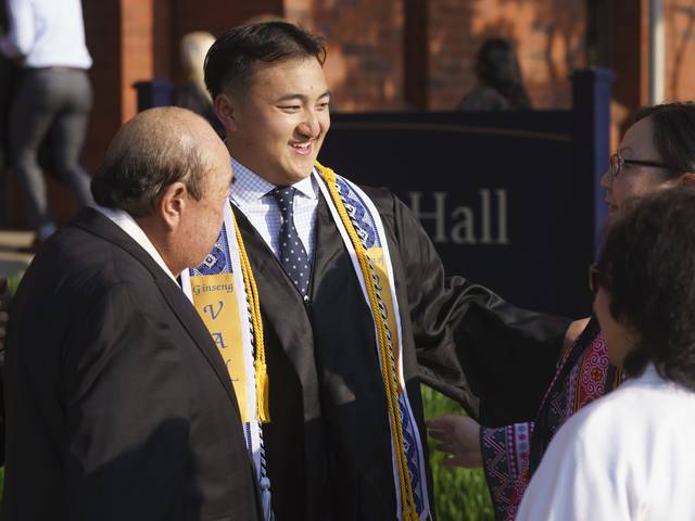 male student greeting family outside commencement ceremony