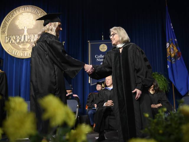 two women on stage at commencement shaking hands
