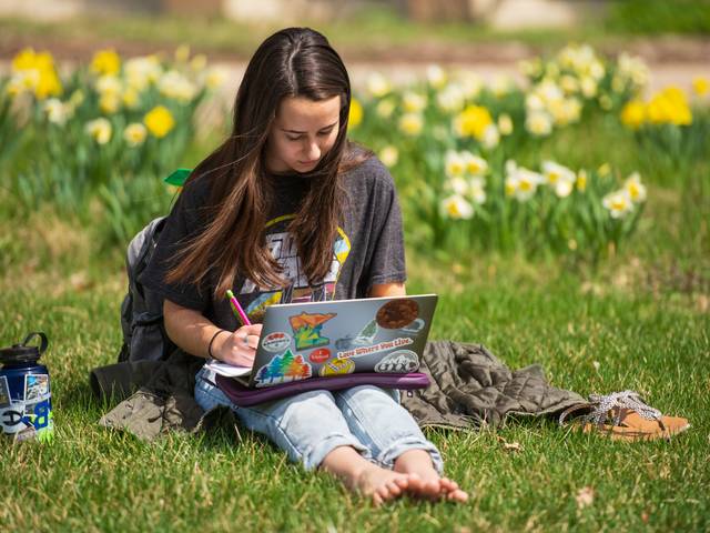 student studying on campus mall , flowers in the background
