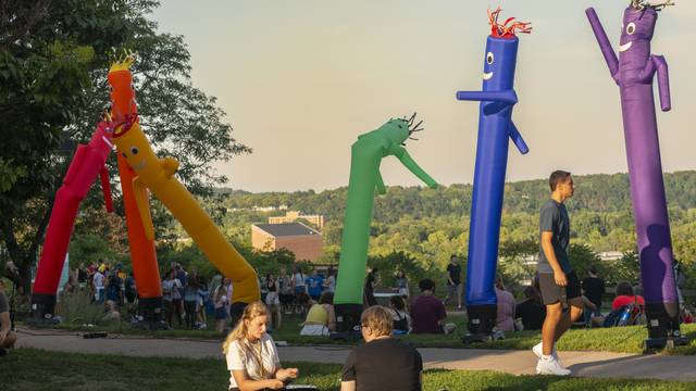 Rainbow inflatable people and students walking past