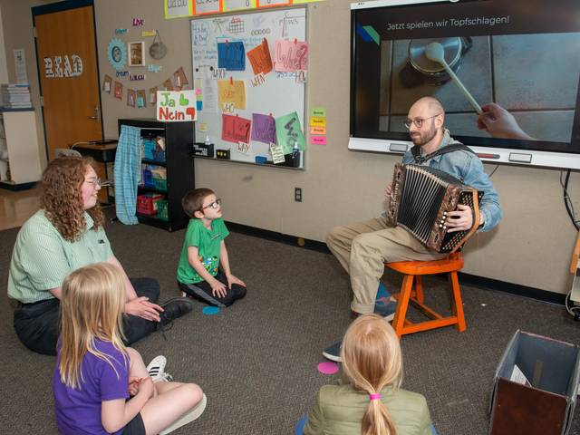 Two student teachers playing music for elementary students in a classroom