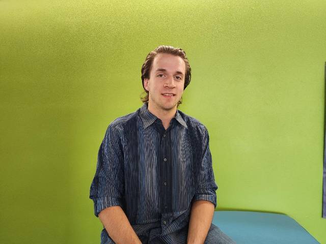 student smiling in front of green background