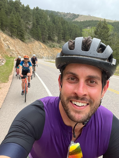 close up shot of male bike rider in a mountain scene with other riders int he background