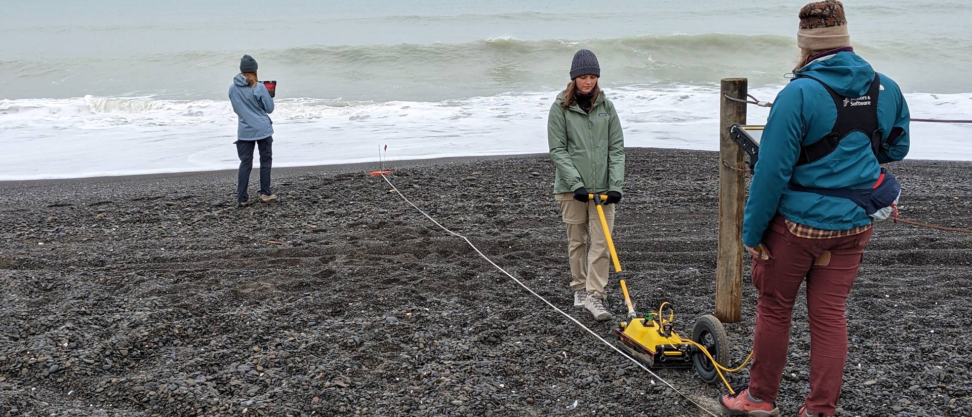 students on a rocky beach using geothermal radar in New Zealand