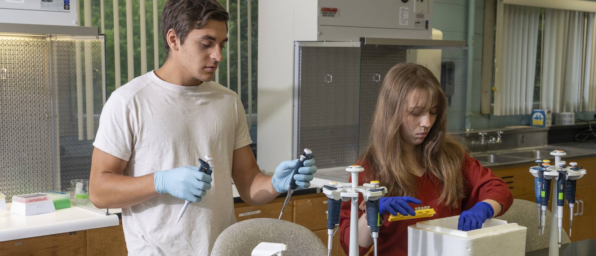 two students in biology lab filling sample tubes into a cooler